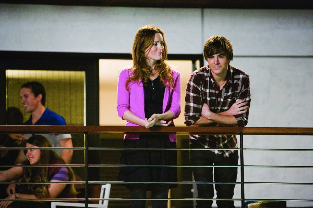 Leslie Mann and Zac Efron standing side by side at a balcony railing.