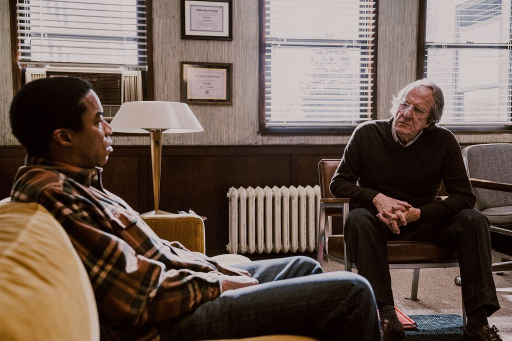 Allen Nelson sits on a couch in a wood-panelled therapy office while Dr. Daniels watches him from an armchair across the room.