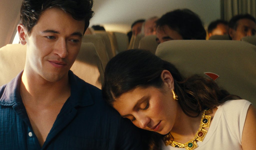 Emily Bader resting her head on Tom Blyth’s shoulder on a plane.