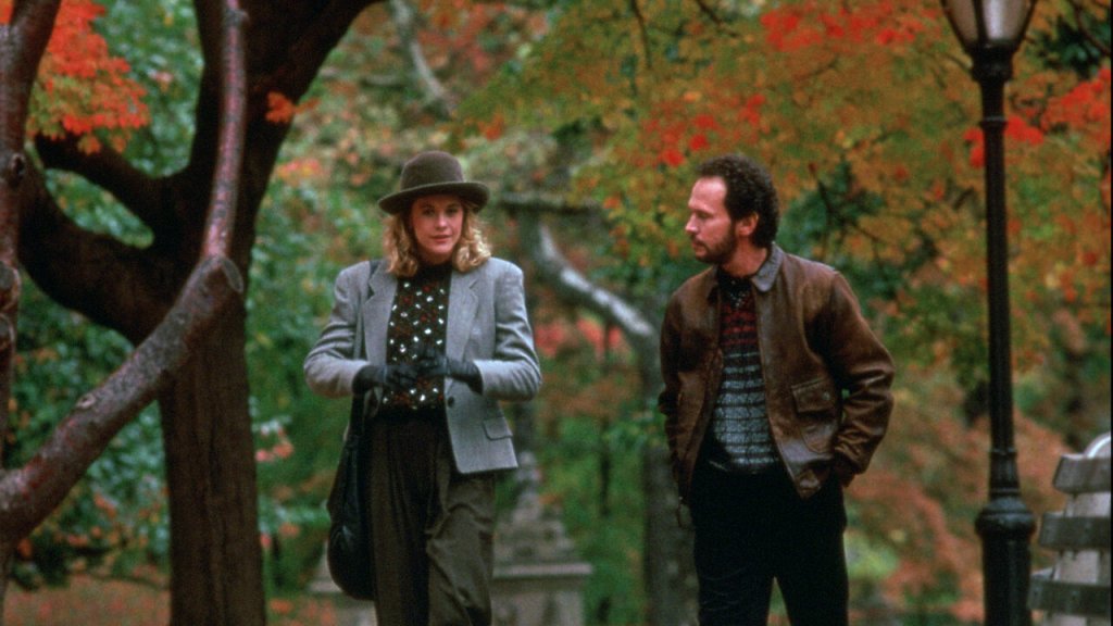 Meg Ryan and Billy Crystal walking through a park full of autumn leaves.