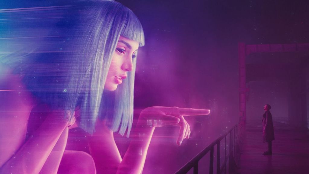 A giant pink hologram of Ana de Armas pointing down at Ryan Gosling on a bridge in Blade Runner 2049.