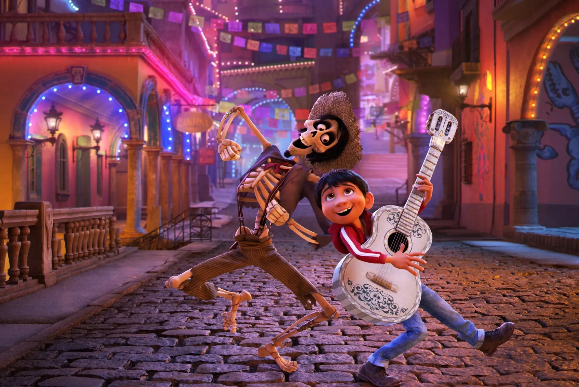 Héctor, a skeleton in a straw hat, dancing next to Miguel playing a white guitar on a cobbled street lit with colorful lights and papel picado in Coco.
