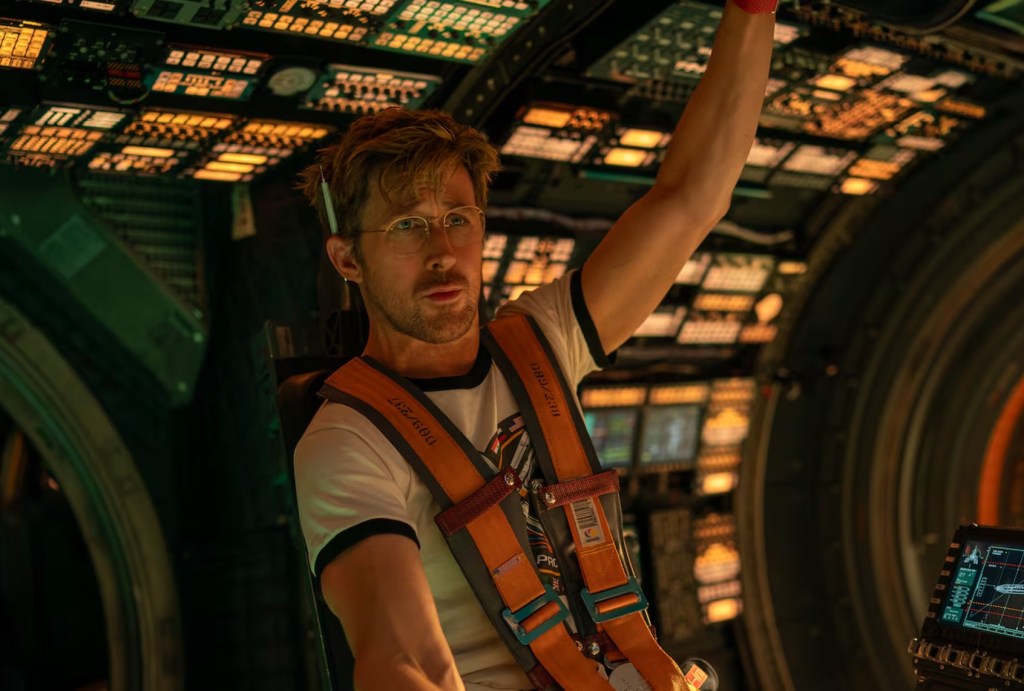 Ryan Gosling in a safety harness, reaching up to a control panel inside a spaceship in Project Hail Mary (2026).
