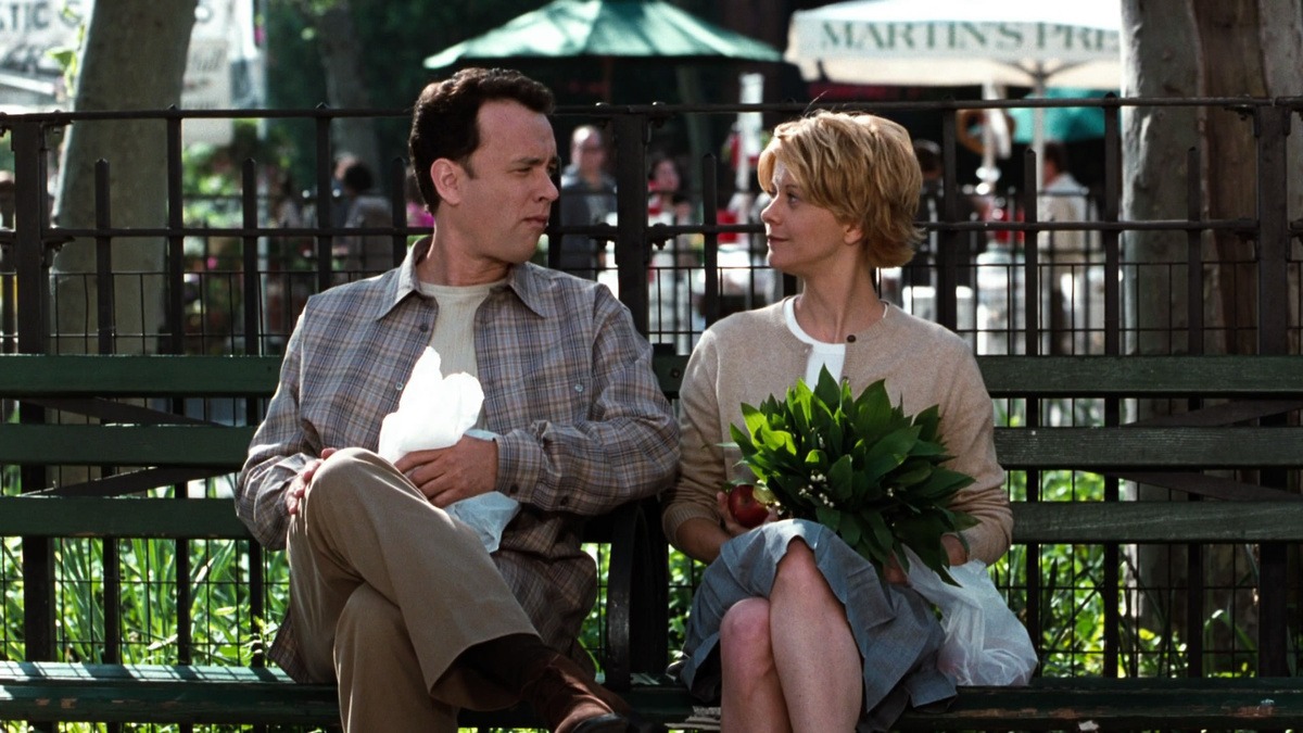 Tom Hanks and Meg Ryan sitting on a park bench in New York, she holding a bunch of flowers, in You've Got Mail.